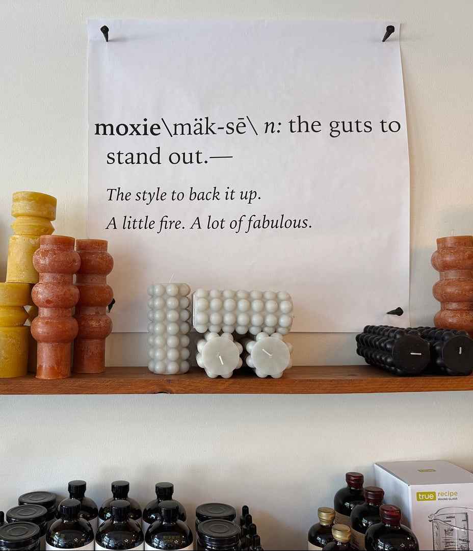 Shelf with decorative items and a definition of 'moxie' on a poster.
