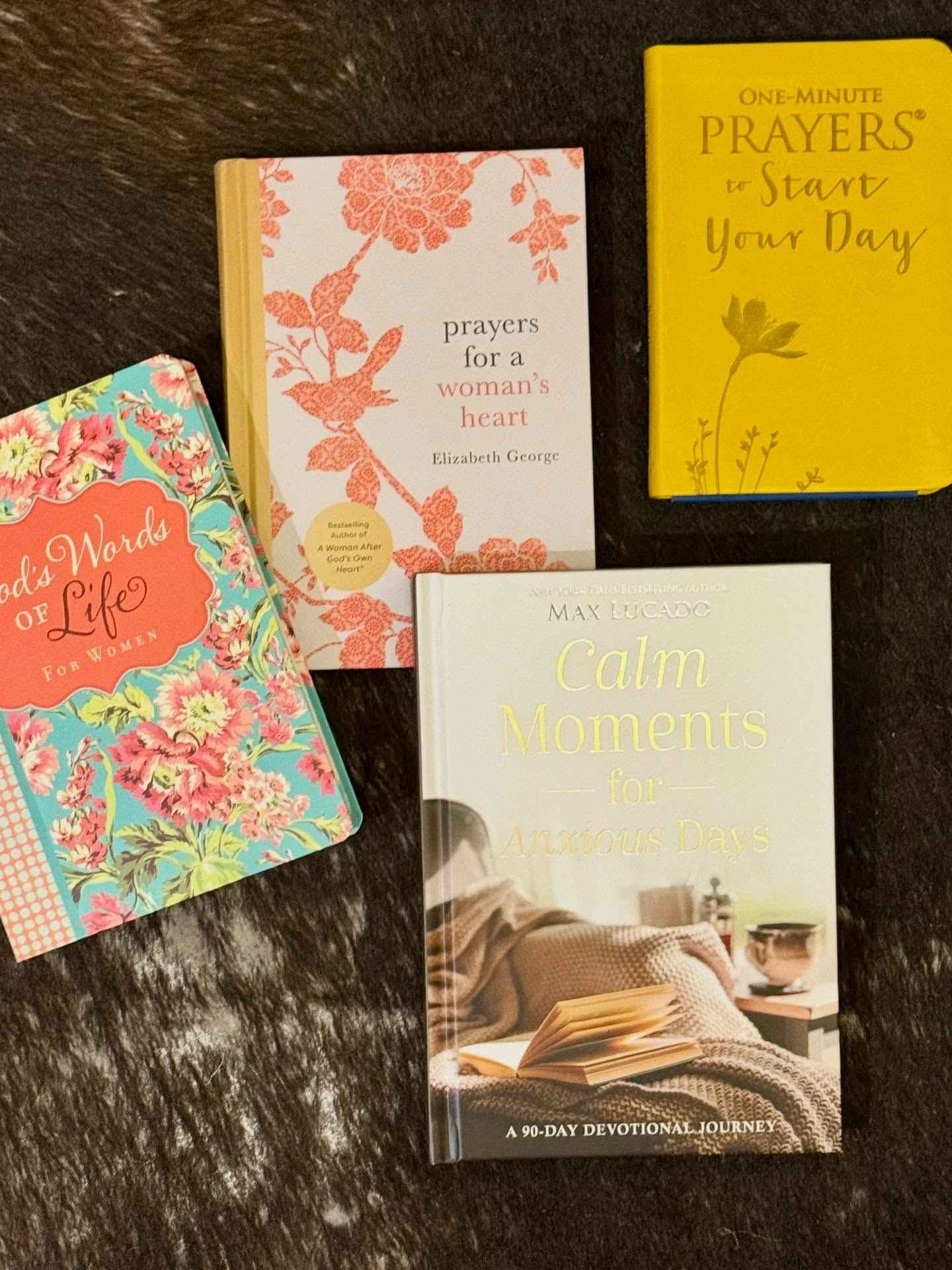 Four books on a dark surface with floral and text designs.