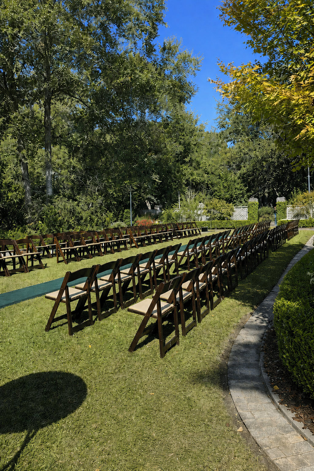 Row of wooden chairs set up on a grassy area with trees in the background