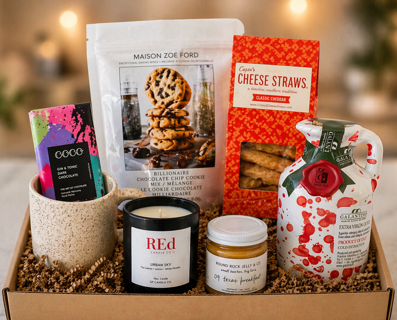 Gift box with assorted items including a candle, chocolate bar, and cheese straws.