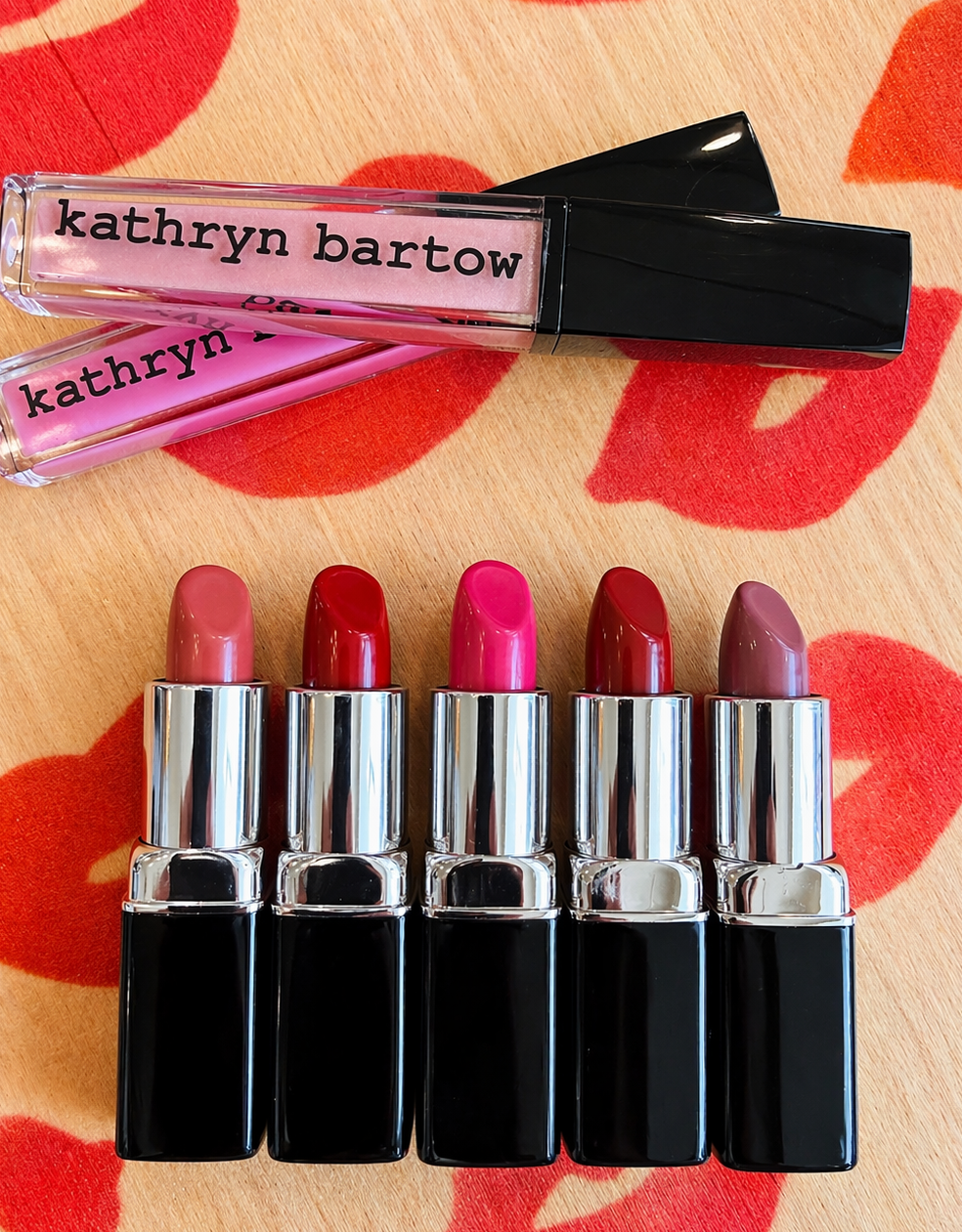 Set of lipsticks with 'kathryn bartow' branding on a red and beige background