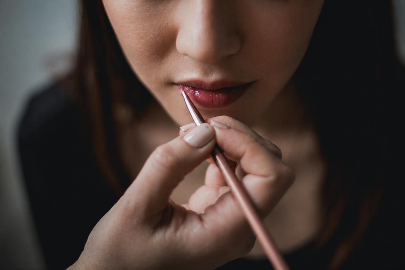 Close-up of a person applying lipstick with a brush.
