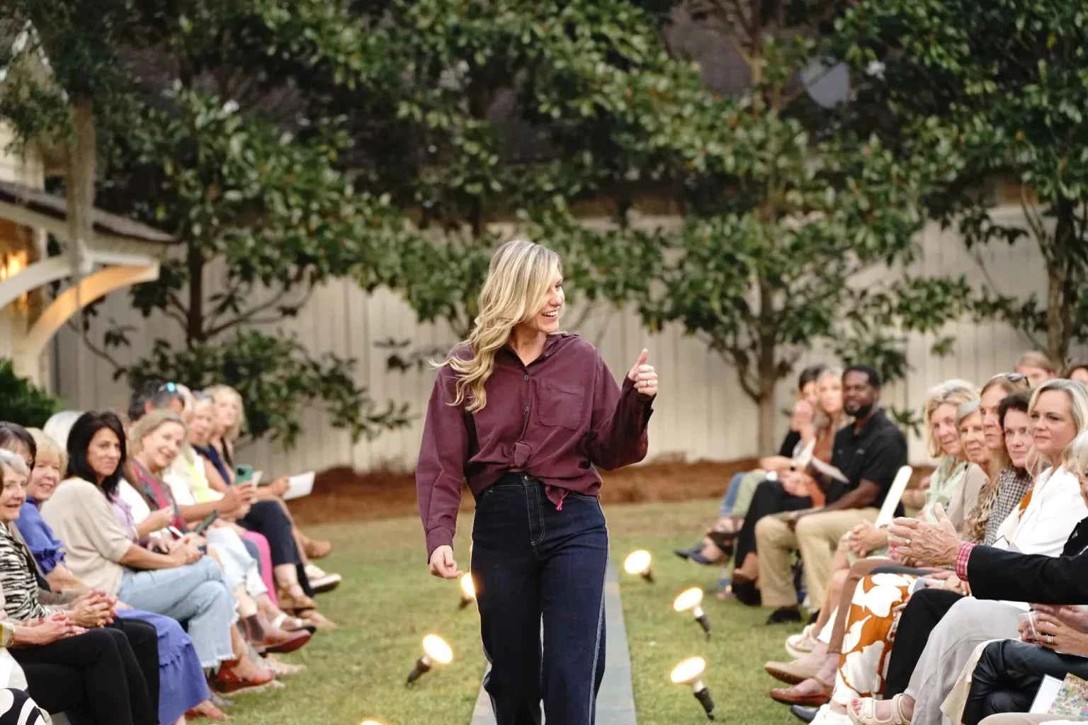Woman giving a thumbs-up to an audience outdoors