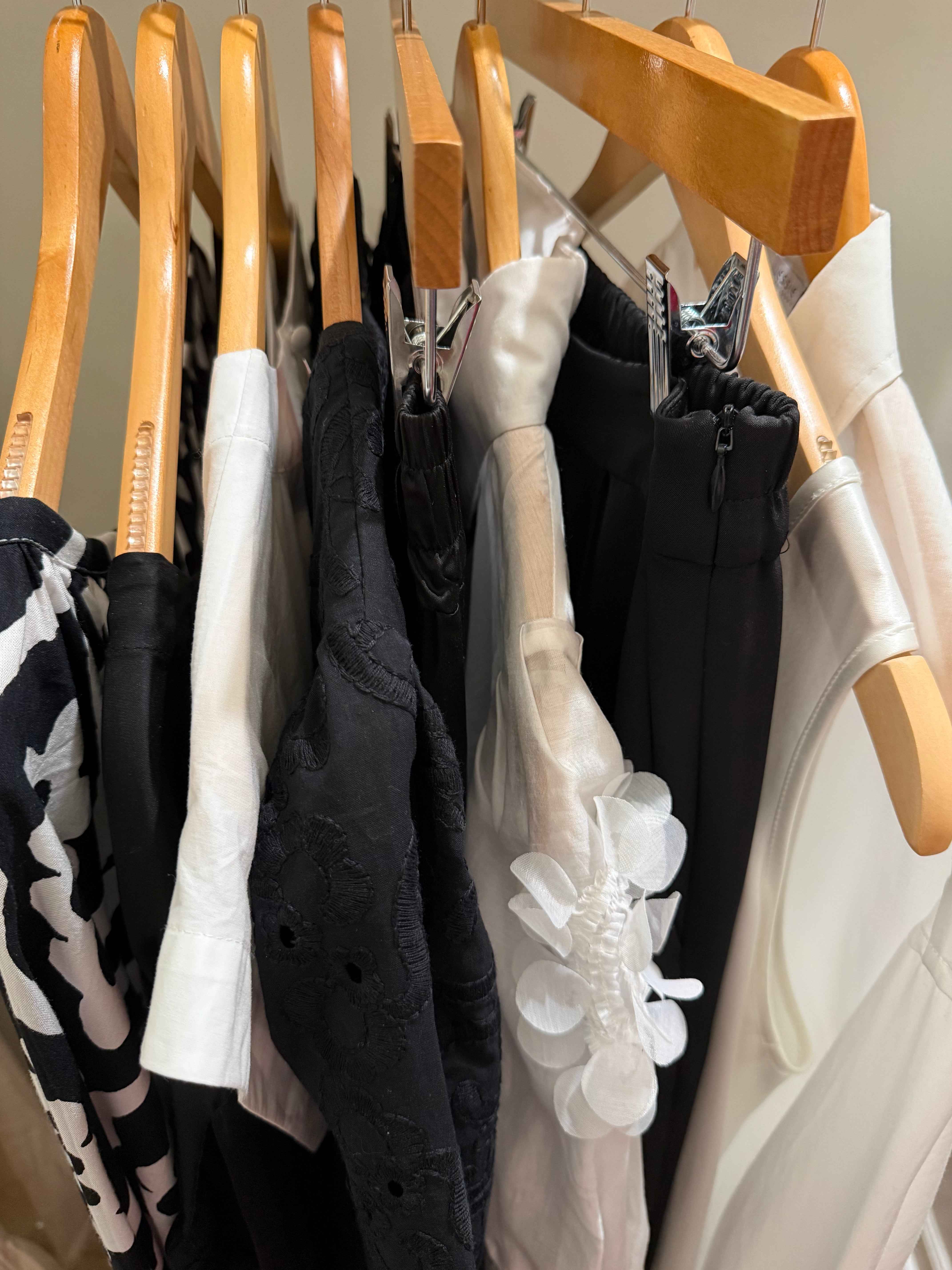 Stack of folded clothes on wooden hangers against a neutral background