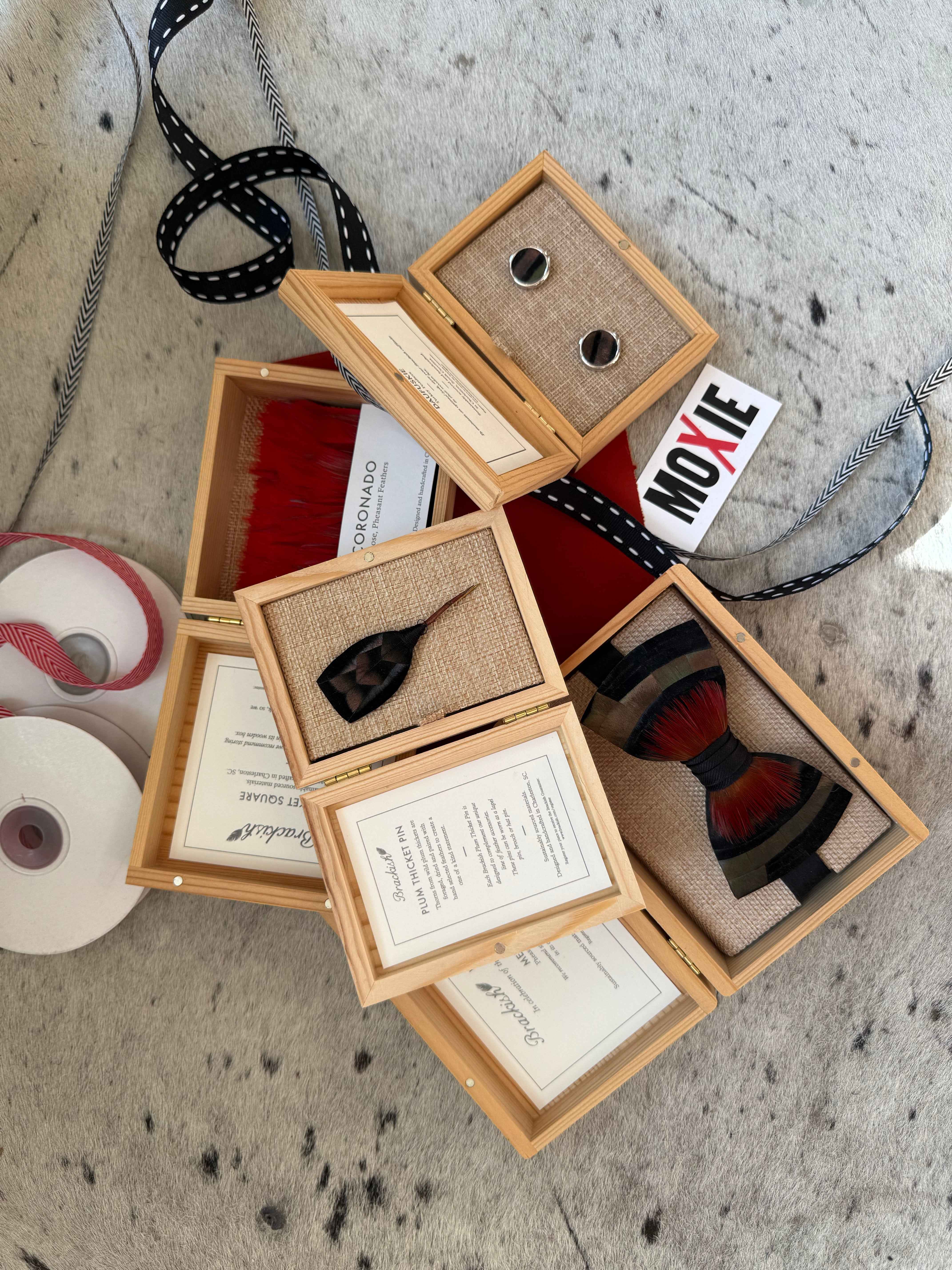 Wooden jewelry display box with necklaces and accessories on a textured surface