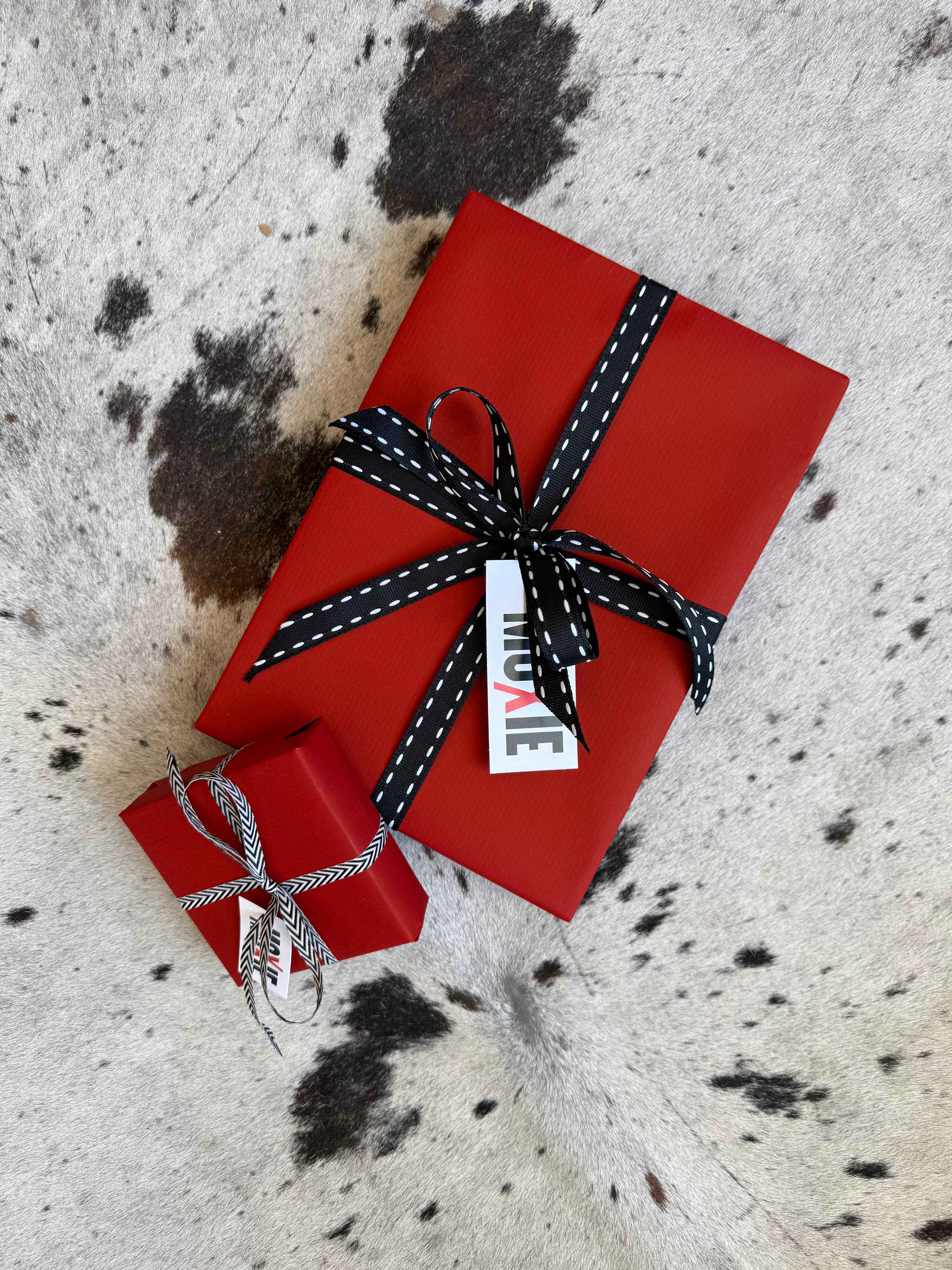 Red gift box with a black and white ribbon on a textured surface