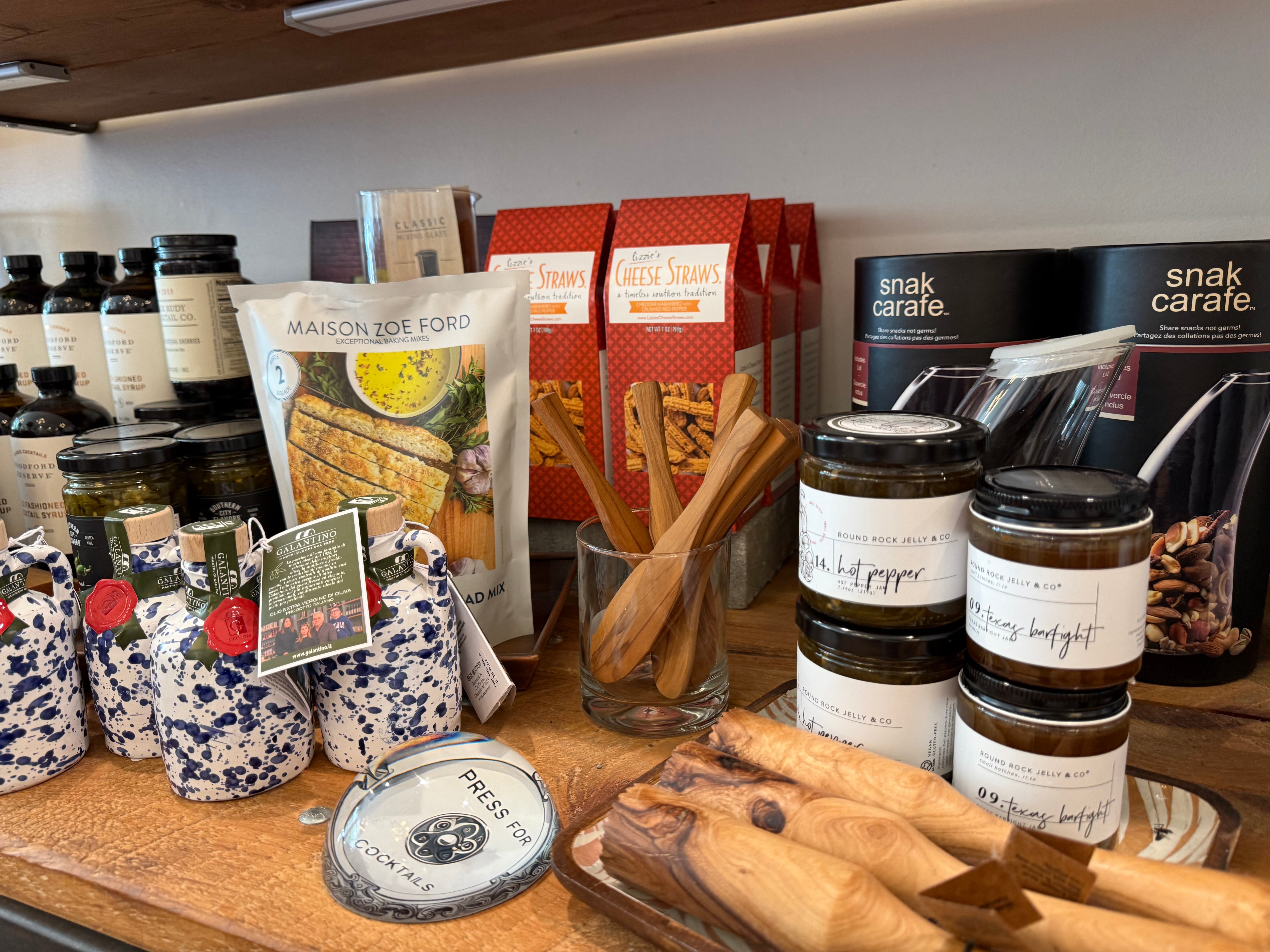 Display of various food items including jars, packets, and wooden spoons on a shelf.