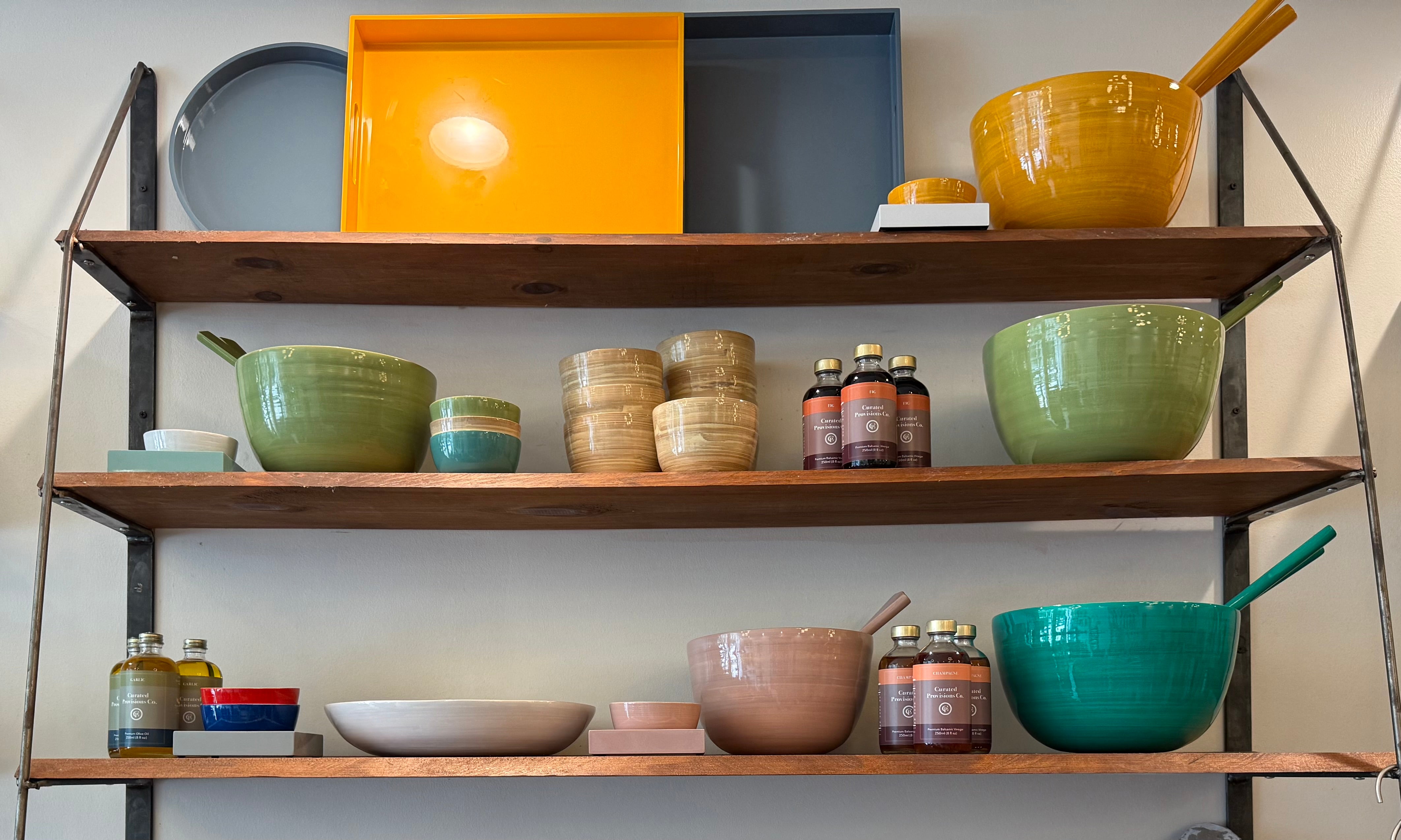 Wooden shelves with colorful bowls and kitchen items against a white wall