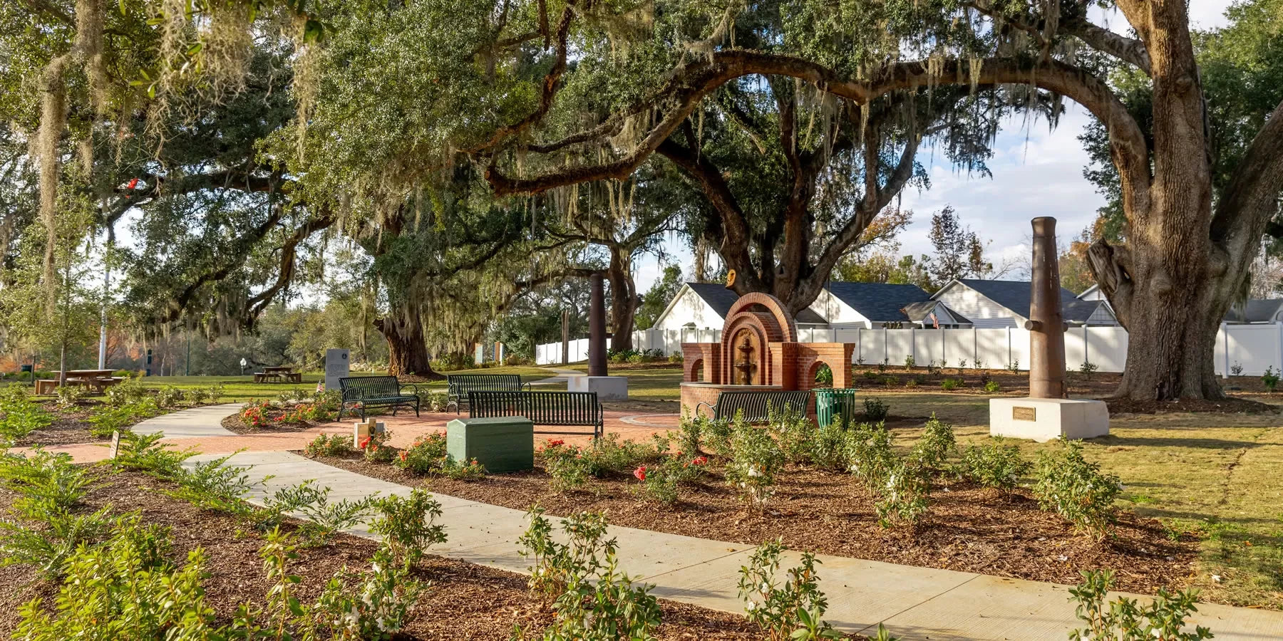Garden area with a large tree and architectural elements in the background