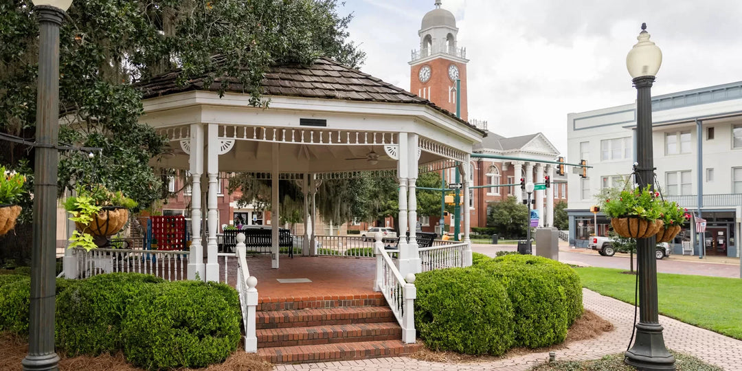 Gazebo in a park with a clock tower and buildings in the background