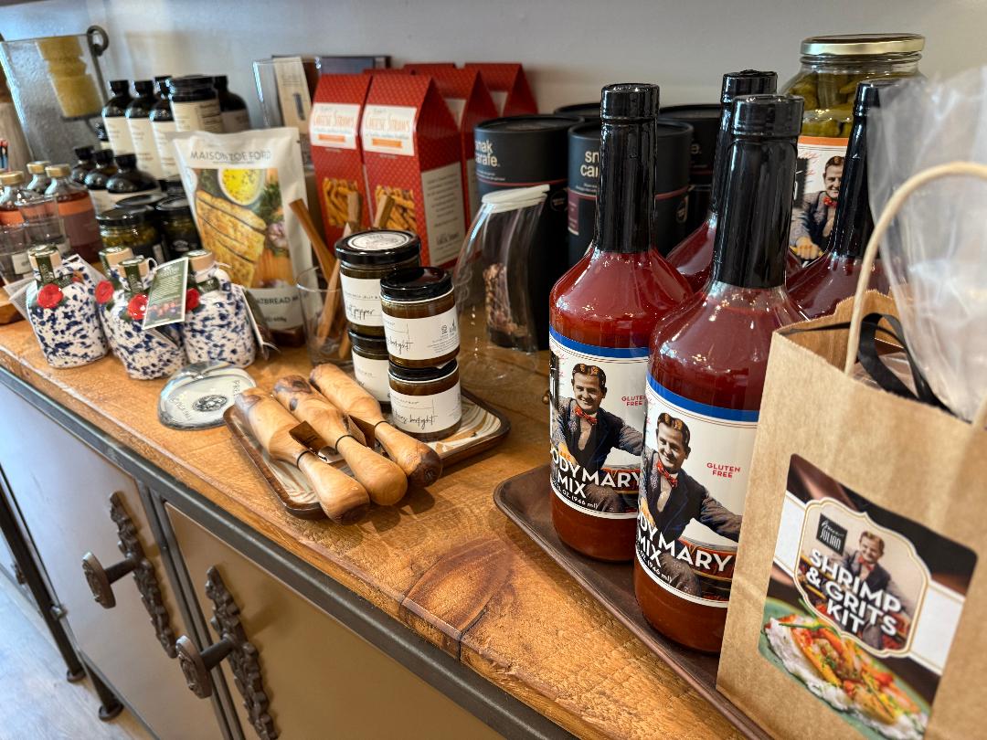 Assorted condiments and sauces on a wooden counter with a paper bag.